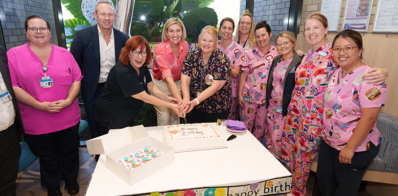 A diverse group of people joyfully cutting a cake together