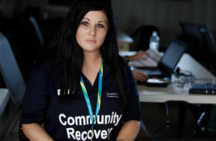 A woman with long dark hair and wearing a Queensland Government community recovery polo shirt
