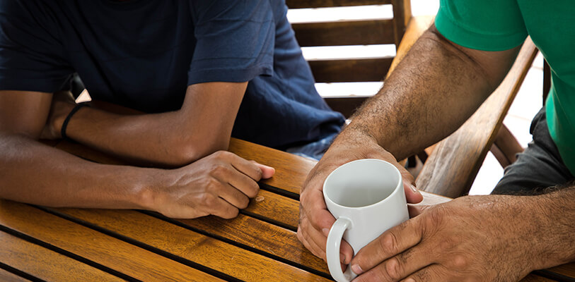 two men seated at a table, enjoying a cup of coffee