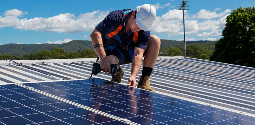 A man installs a solar panel on a rooftop